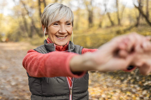 istock Smiling senior woman in park stretching hands 1489695772