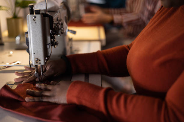 istock Close up of a black designer sewing material on a machine in a studio. 1489700490