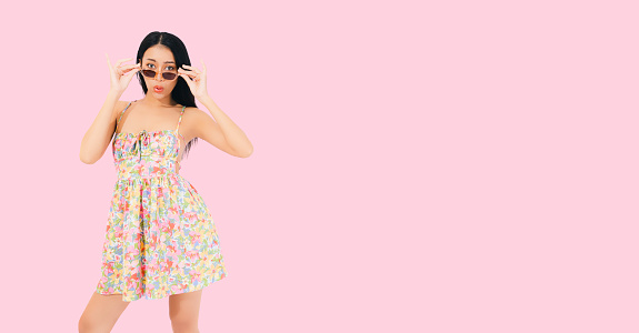 Joyful Asian lady in summer stand on pink background Debonair girl in dress excited Portrait young beautiful smiling asia female in trendy summer clothes Carefree happy woman wear sunglasses has fun