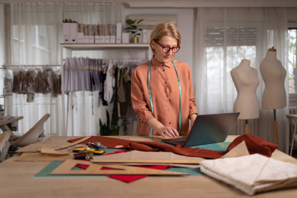 istock Mature female tailor working on laptop in a design studio. 1489702162