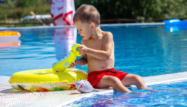 istock Happy child in the pool playing with a water gun. 1489714134