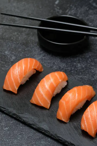 Closeup of salmon nigiri sushi and isolated on dark background.