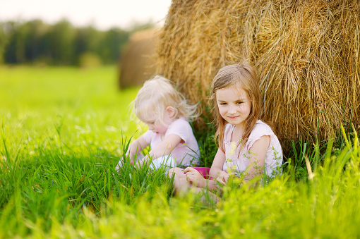 Farm children sitting in a large tractor wheel.Please browse: