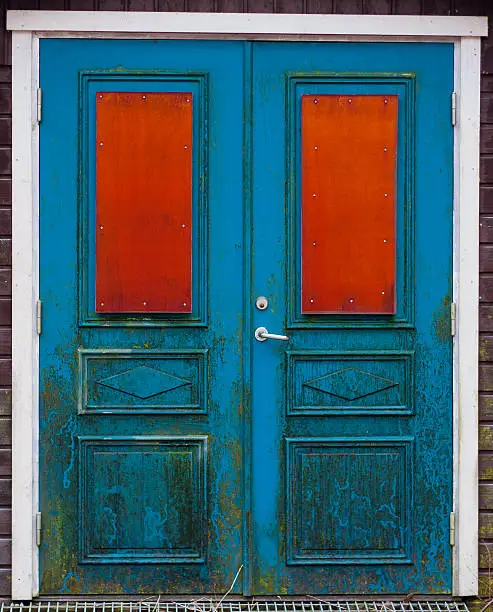 Weathered blue doubledoor with red "windows"