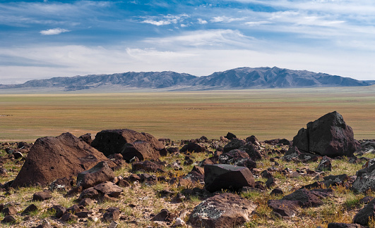 Steppe landscape with mountains in the background and stone boulders in the foreground in Mongolia, Central Asia