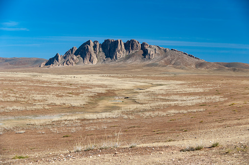 Rock formation on the horizon in the steppe landscape of the Gobi Desert, Mongolia, Central Asia