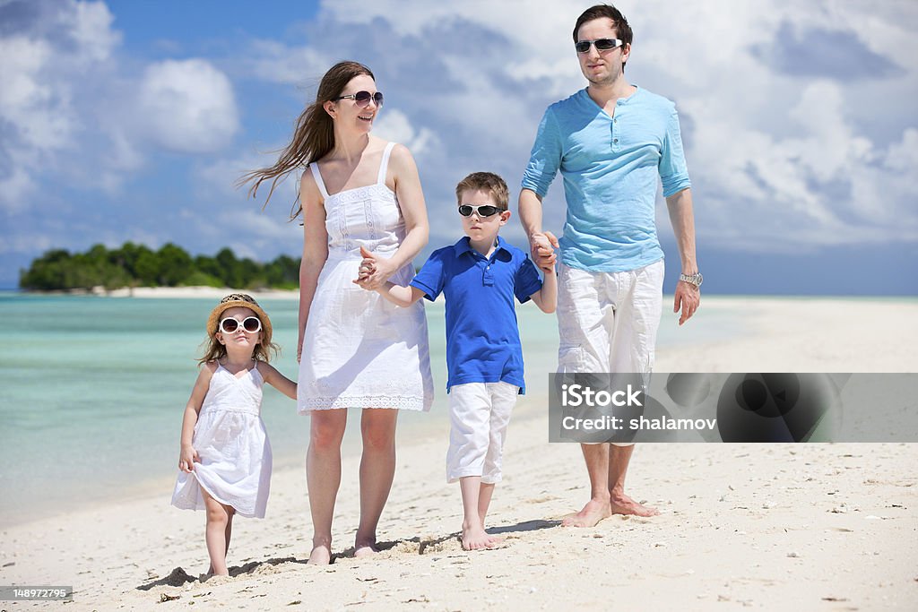 Happy family on tropical vacation Young beautiful family with two kids walking at beach Adult Stock Photo