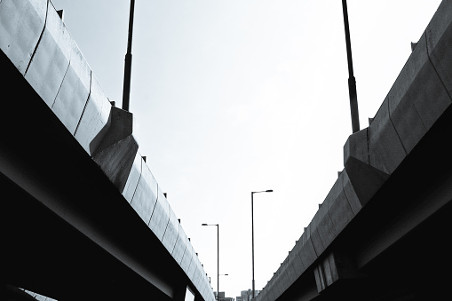 Black and white shot of two urban bridges with streetlights converging and diverging