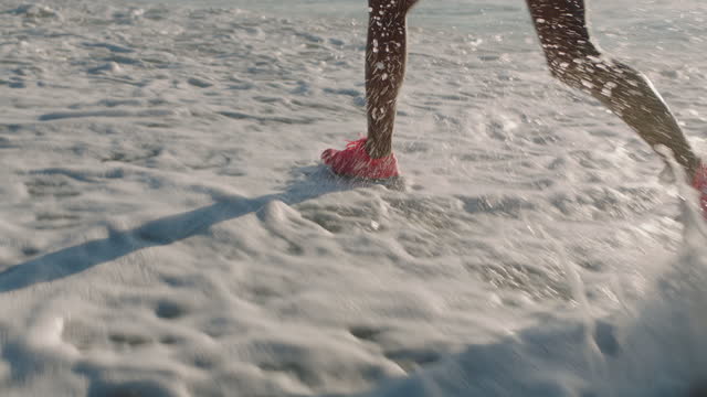 african american woman legs running on beach splashing water exercising fitness workout female runner athlete jogging in seaside ocean water