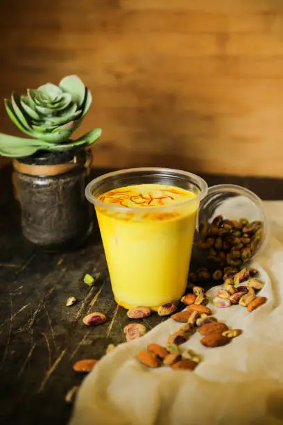 Photo of Badam sharbat, Almond milk syrup with saffron served in glass isolated on table top view of drink