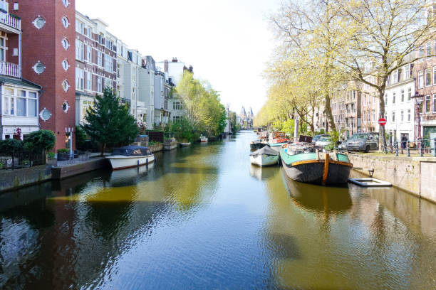 View of the Lijnbaansgracht in Amsterdam with various houseboats and other vessels. The towers of the famous Rijksmuseum is visible in the far background.