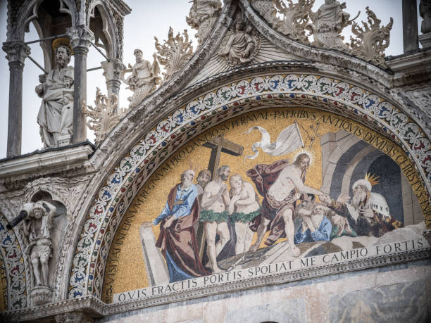 Venice, Italy - February 12, 2024: Golden mosaics depicting biblical scenes and latin inscriptions adorn the ceiling of St. Mark's Basilica in Venice, Italy, showcasing the rich history and artistry of this iconic landmark