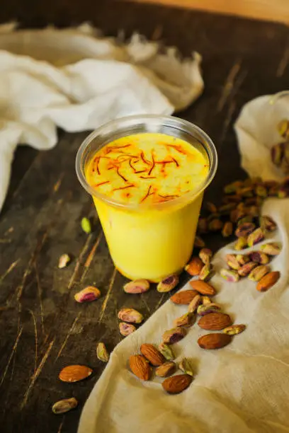 Photo of Badam sharbat, Almond milk syrup with saffron served in glass isolated on table top view of drink