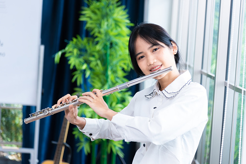 Flute classical instrument profestional player playing song.  A young and elegant Asian woman plays the flute.