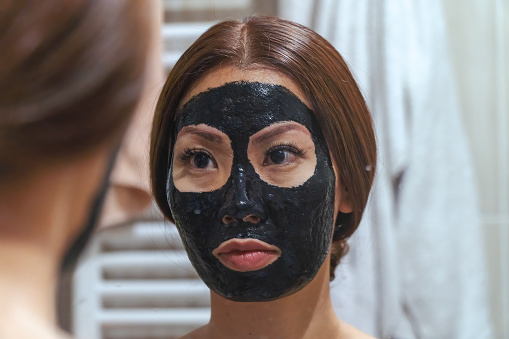 Applying facial mask - beauty product - charcoal facial mask