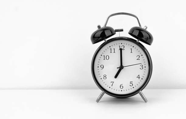 istock Black alarm clock on white wall background 1489756343