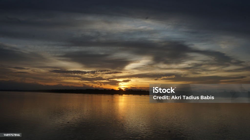 Beautiful orange sunset over the river with the sun and clouds reflected in the water Beautiful orange sunset over the river with the sun and clouds reflected in the water. photographed on the Sesayap river-North Kalimantan Adventure Stock Photo