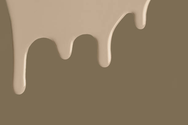 istock Beige liquid drops of paint color flow down on brown background. Abstract umber backdrop with sand fluid drip 1489758579