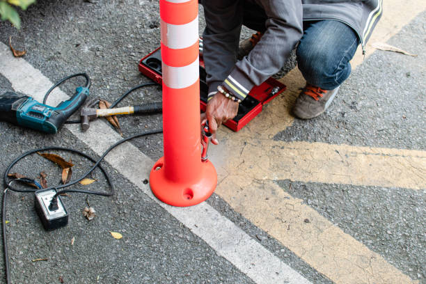 istock Close up a man is working by installing a small traffic cone on the road, a man's hand holding a block wrench to screw the nut to the road. Tools for the work include a drill, hammer, electric cable. 1489764634