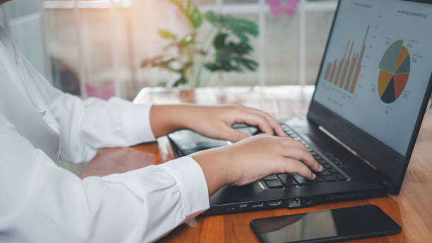 istock Businesswoman using laptop computer on wooden table And she is looking at the graph displayed on the computer screen. business concept 1489767308