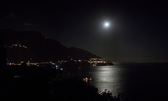 View of the night sea coast illuminated by the bright light of the moon reflecting in the dark water