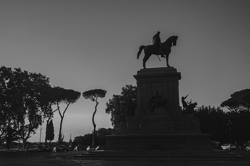 A silhouette of the statue of a man on a horse is in front of a tree. Rome, Italy