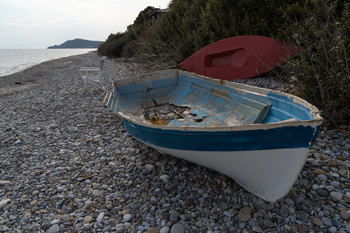 An abandoned broken boat full of holes lying on the seashore in the off season
