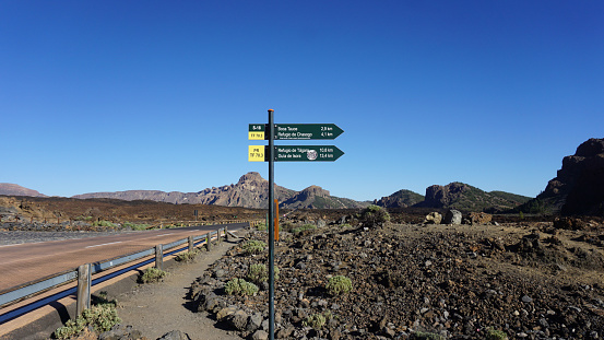 Tenerife, Canary Islands, Spain - May 8, 2023: Boca Tauce road signs in Teide National Park, volcanic landscape on a blue sky background, hiking path