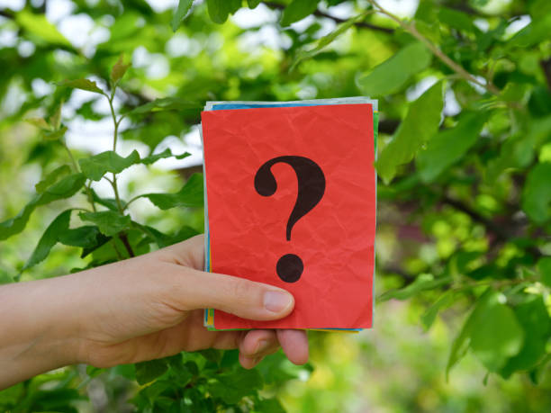 istock A woman holding a stack of colorful paper notes with question marks on them in her hand against a background of foliage 1489770110