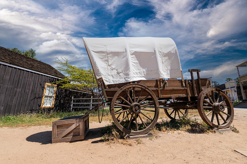 Old weathered wagon in a rural setting against a cloudy sky background.