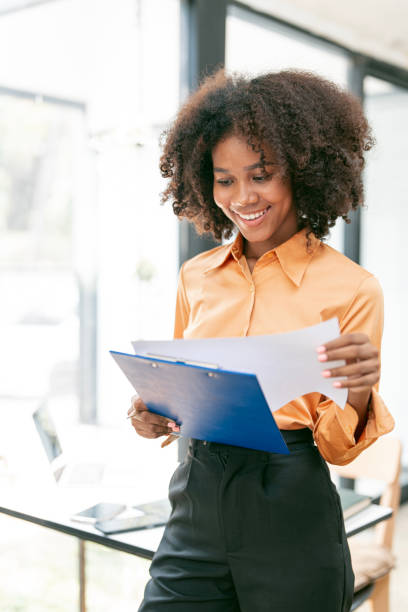istock Young black woman working on document standing in office. 1489775888