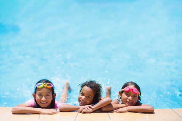 Kids in swimming pool. Children swim. Family fun. Kids play in swimming pool. Children learn to swim in outdoor pool of tropical resort during family summer vacation. Water and splash fun for young kid on holiday. Sun protection for child and baby. game resort pictures stock pictures, royalty-free photos & images