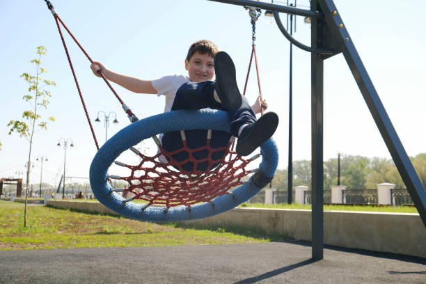istock Cute boy is riding on a swing on the embankment. 1489783710