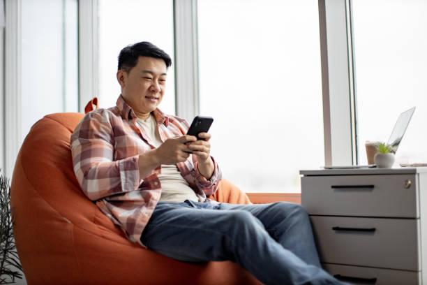 istock Asian man with smartphone in hands resting at office 1489786298