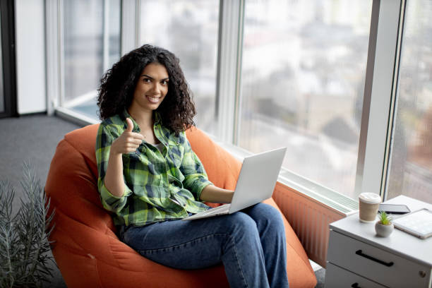 istock Businesswoman posing in beanbag with laptop at work 1489786427