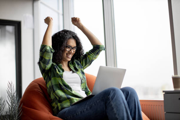 istock Female raising fists while reading email on laptop in office 1489786511