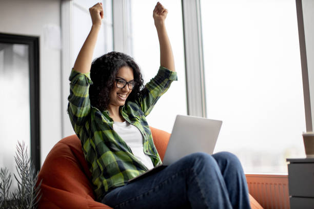 istock Female raising fists while reading email on laptop in office 1489786543