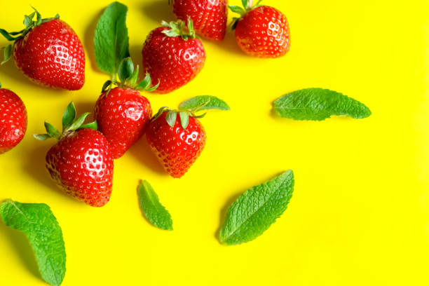 istock Strawberries with mint on a yellow background. Ingredients for summer refreshing dishes. Sunny background with red strawberries and green mint. 1489794211
