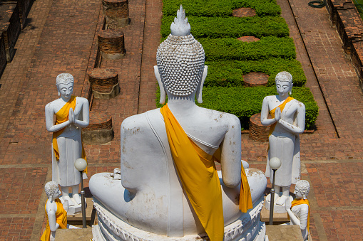 Statues tributing to a huge sitting Buddha statue monument in temple town Ayutthaya, Thailand