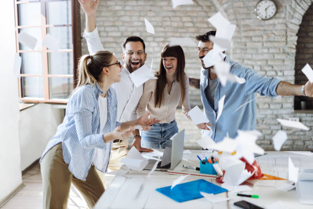 istock Cheerful business colleagues celebrating  success while throwing papers in the office 1489796217
