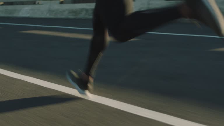 close up athlete legs running on road fit runner jogging sprinting endurance exercise in urban city morning at sunrise