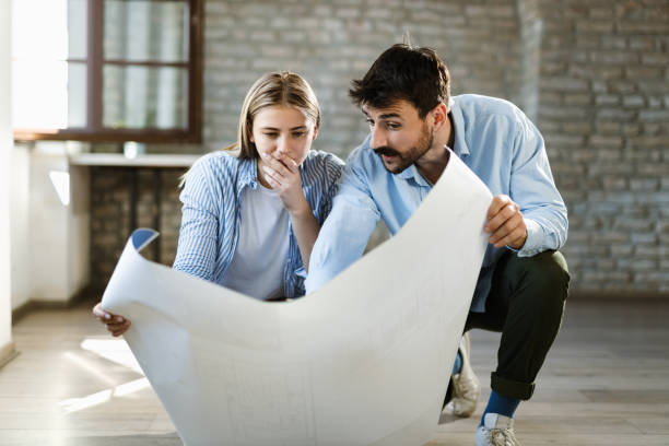 istock Young couple analyzing housing plan in their new home 1489800627