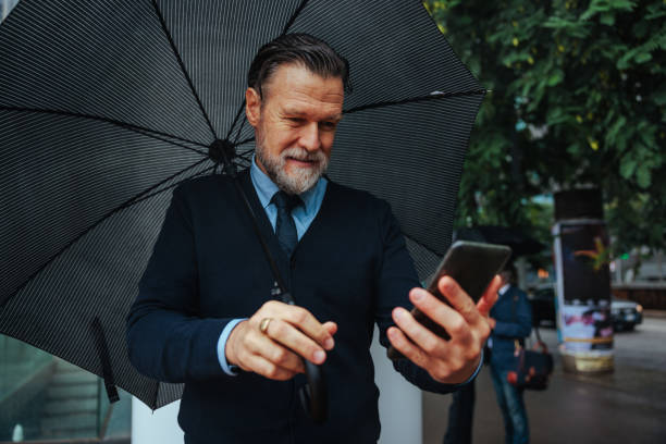 istock Joyful businessperson using telephone outside on rainy day. 1489800710