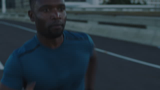 attractive young african american man running in city focused athletic male exercising fitness workout on urban road background close up