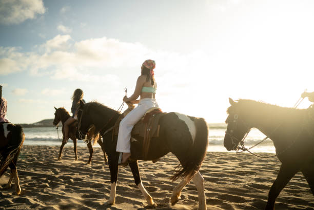 istock Female friends during horseback riding on the beach 1489803830