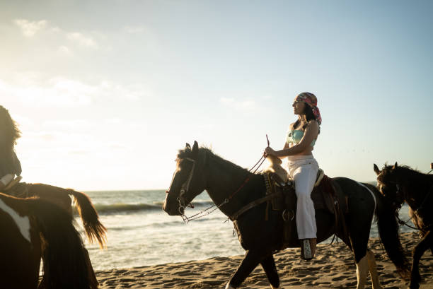 istock Female friends during horseback riding on the beach 1489803833