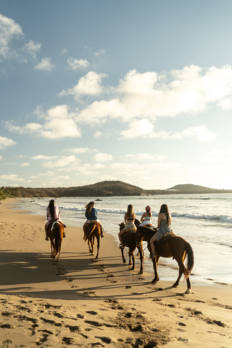 Female friends during horseback riding on the beach