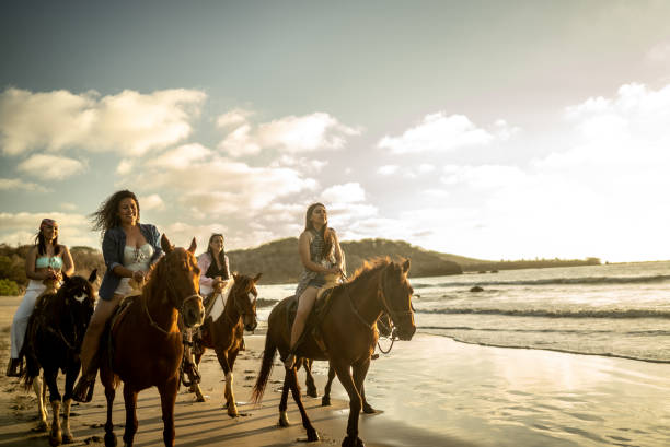istock Female friends during horseback riding on the beach 1489804813