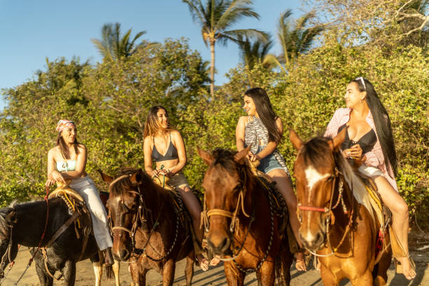 istock Female friends talking during horseback riding on the beach 1489804843