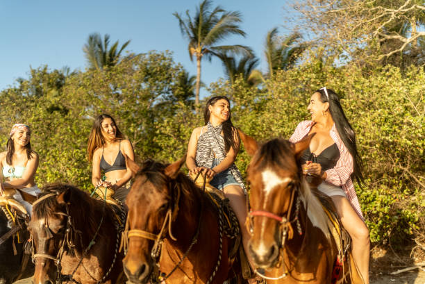 istock Female friends talking during horseback riding on the beach 1489804844